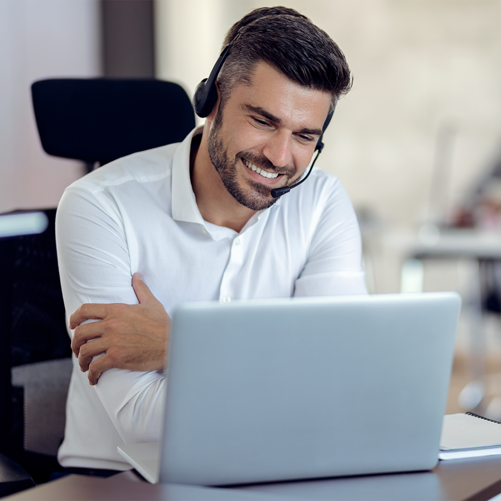 atendente de call center com headset sorrindo olhando para tela de notebook